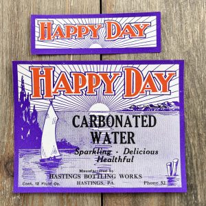 2 Different vintage Happy Day Carbonated Water labels featuring a monochrome blue sailboat and sunset.