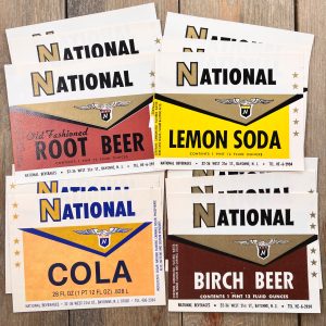 Four different piles of three National soda labels in shades of brown and yellow