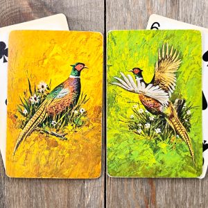 4 Assorted vintage playing cards in 2 piles - one is a standing pheasant on a yellow background and the other is a flying pheasant on a green background