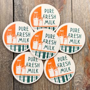 6 Vintage white, orange, and green Pure Fresh Milk caps with an illustration of a glass milk bottle and a glass of milk
