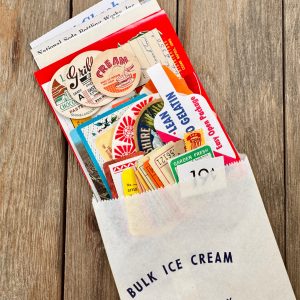 A vintage white Ice Cream paper bag full of vintage food and drink themed ephemera